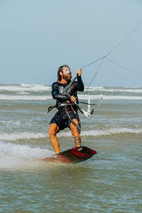 Kiter navegando de frente sobre agua turquesa