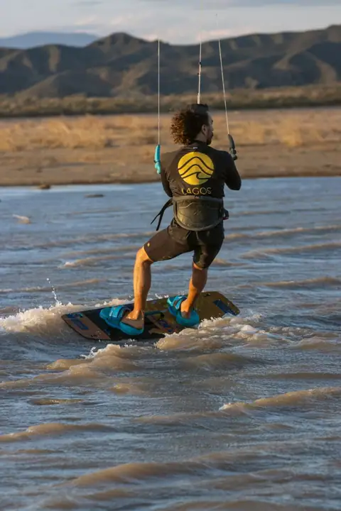 Navegando con la tabla sobre el agua marrón del embalse