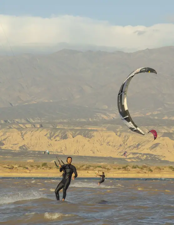 Kiter navegando con kite plateado frente a las montañas