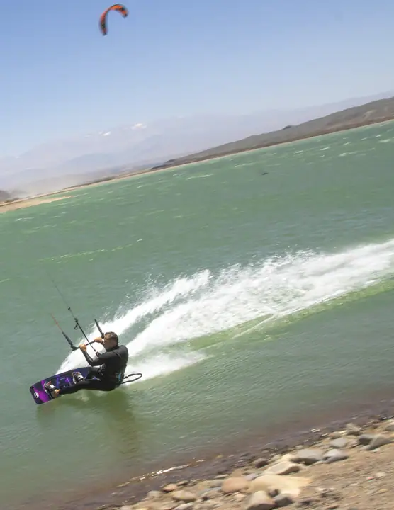 Kiter haciendo un carving con spray sobre el agua verde del embalse