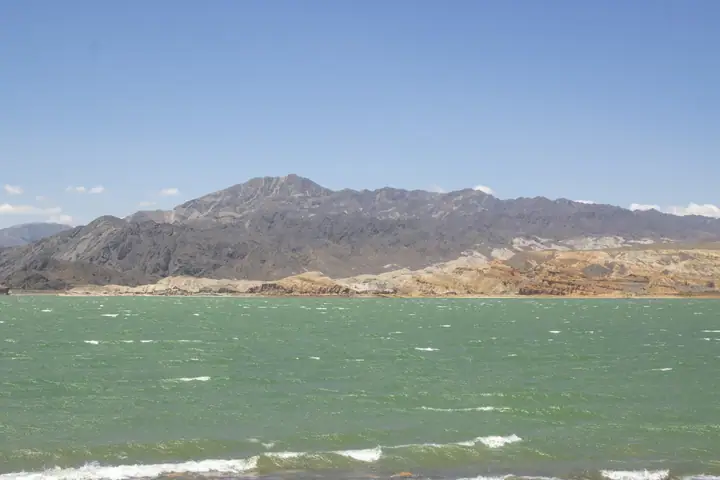 Kiter navegando con kite azul frente a la costa y la montaña