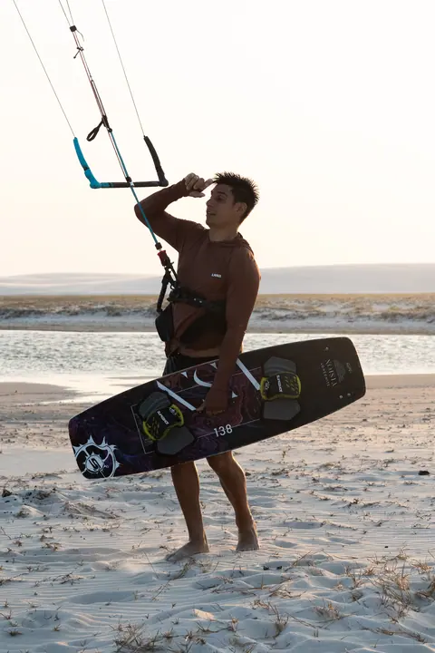 Kiter caminando en el agua con la tabla bajo el brazo entre sesiones