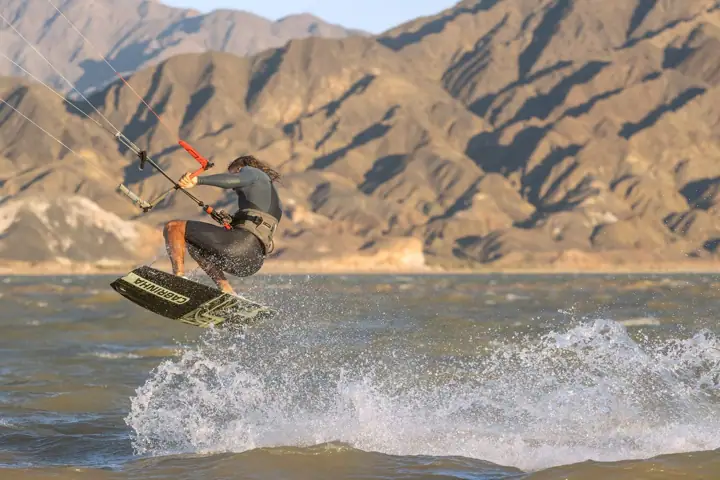 Kitesurfista saltando con spray de agua en el embalse