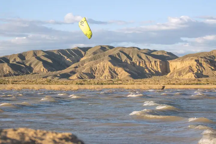 Kite amarillo sobre el agua frente a la montaña