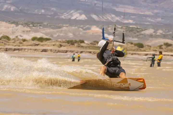 Salto con kite naranja sobre el agua