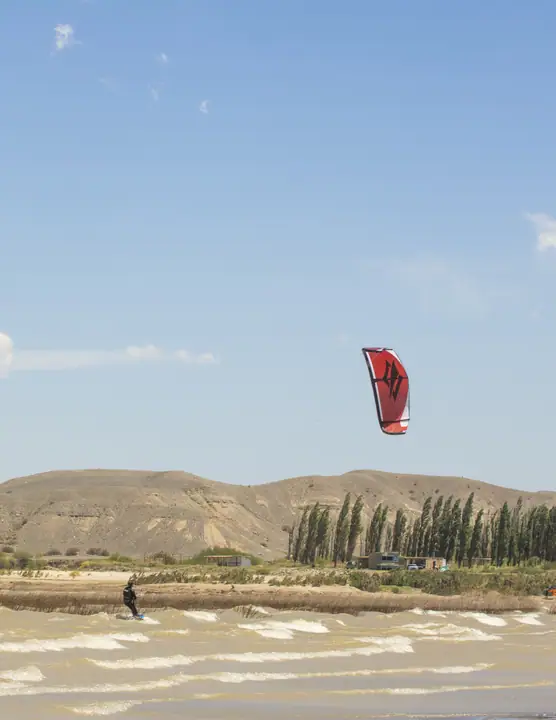 Kite rojo en el cielo sobre la orilla del embalse en un día de viento