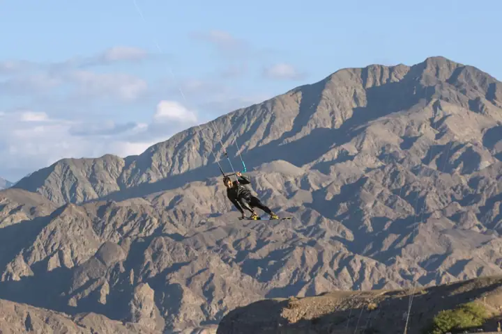 Kitesurfista navegando frente al paredón de montaña