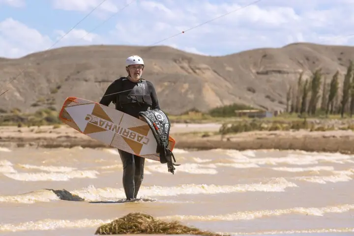 Kitesurfista saliendo del agua con la tabla al hombro