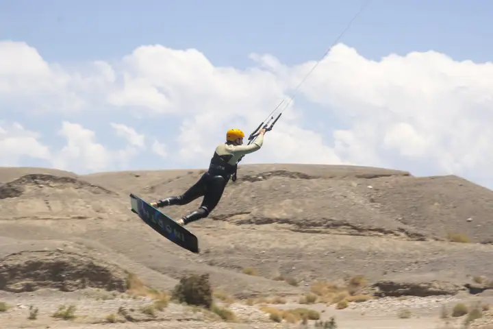 Kiter saltando sobre el agua frente a la costa rocosa del embalse