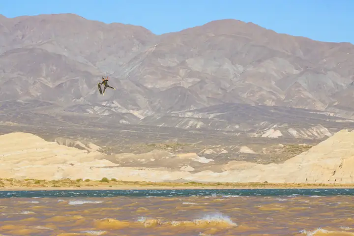 Salto alto de kite sobre el embalse con las badlands de fondo