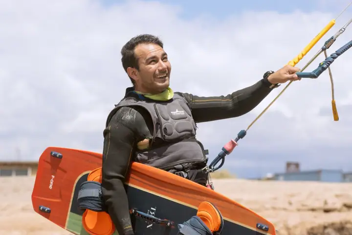 Kitesurfista cargando su tabla y barra