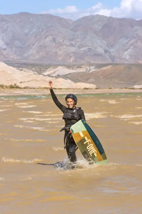 Kitesurfista celebrando con la tabla en la mano