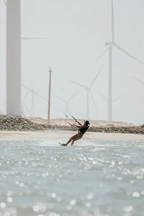 Kiter navegando contra el reflejo del sol frente a los molinos